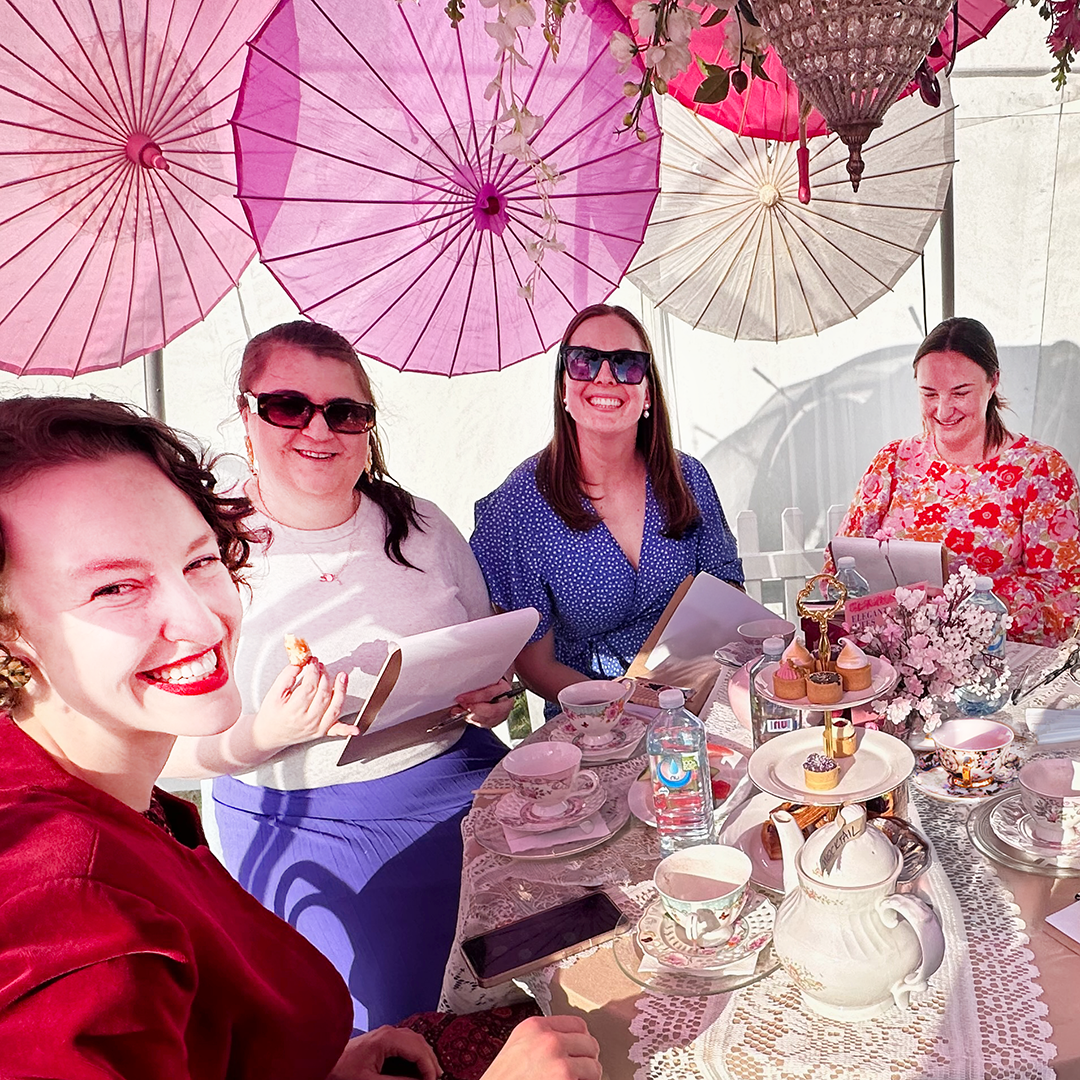 Group enjoying the Cocktail High Tea party with pink and white parasols above them at Floriade. Collectors and Explorers Gin.