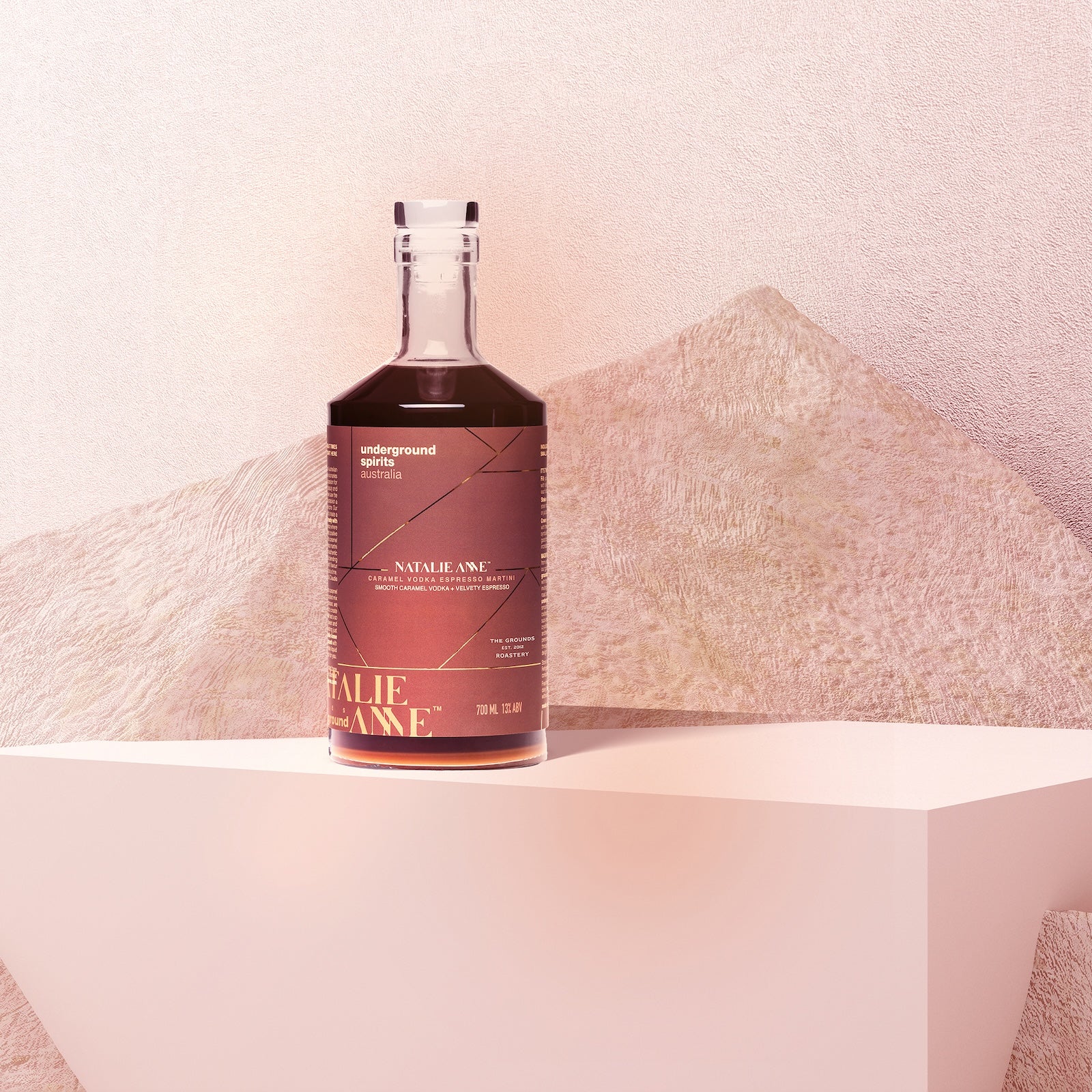 Underground Spirits Australia x Natalie Anne Limited Edition Caramel Espresso Martini sits elegantly on a minimalist pedestal, surrounded by abstract textures and warm lighting, embodying the premium craftsmanship and innovative flavours of Underground Spirits Canberra